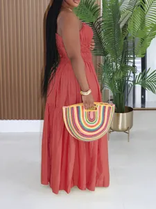 Detailed side view of bohemian coral tiered maxi dress styled with a colorful woven bag