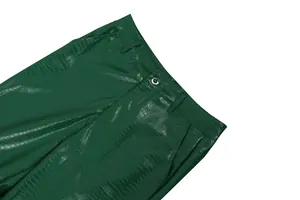 Detail of green faux crocodile leather pants showing waist button and textured fabric
