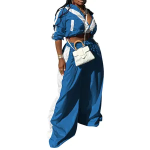 Detail des zweiteiligen Sportanzugs für Damen mit blau-weißem Colorblock-Design aus Webstoff.
