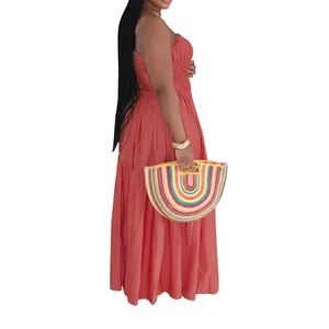 Model in coral bohemian tiered maxi dress holding a colorful rainbow straw bag