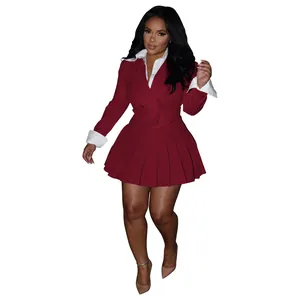 Detail view of a wine red two-piece blazer set featuring a pleated skirt and white cuffs