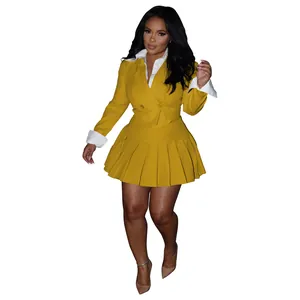 Detailed view of yellow blazer and pleated skirt set with white contrast cuffs.