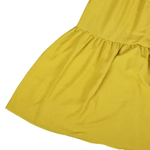 Macro view of yellow bohemian tiered dress fabric showing soft texture and ruffle detail