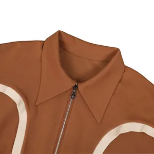 Close-up detail of a brown collared sweatshirt featuring a zipper and white curved trim