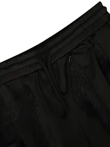 Detailopname van een zwarte broek met trekkoord en unieke gelaagde franjestexturen