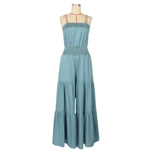 Detailed view of light blue smocked denim jumpsuit with tiered wide legs.