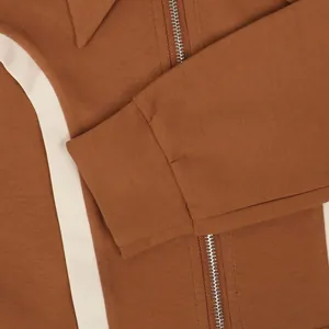 Detailed shot of brown cotton sports jacket showing metal zipper and ribbed cuff