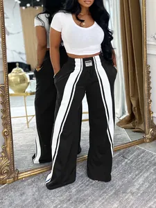 Vue détaillée du pantalon noir large à taille haute avec bandes latérales blanches.