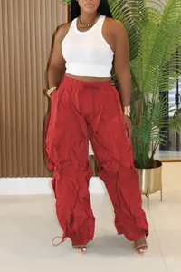 Detailed view of red oversized pleated wide-leg pants with ruffles and drawstring