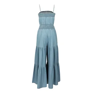 Back view of a light blue denim sleeveless jumpsuit with tiered wide legs and smocking