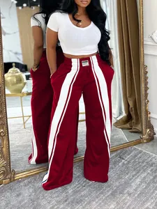 Vue détaillée d'un pantalon de sport large rouge vin avec des bandes latérales blanches.