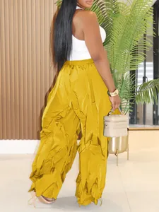 Close-up of yellow wide-leg pleated trousers featuring elegant vertical texture folds.