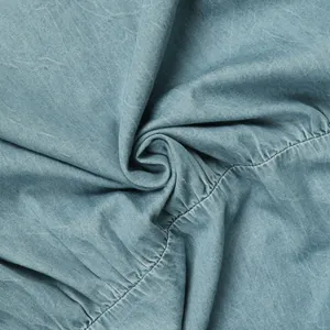 Close-up macro detail of washed blue denim fabric showing gathered seam and texture