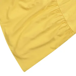 Close-up of the bright yellow fabric texture and gathering detail on a summer maxi dress