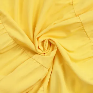 Detailed close-up of vibrant yellow bohemian maxi dress fabric with soft pleated texture.