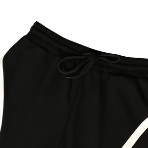 Detail view of black sports pants showing an elastic waistband and white stripes