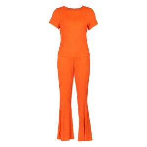 Détail d'un ensemble plissé orange vif à deux pièces avec une texture côtelée ondulée.