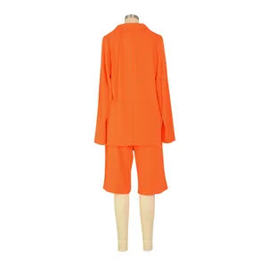 Vista trasera de un vibrante traje naranja de dos piezas para mujer con blazer y shorts.