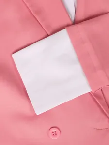 Close-up detail of a pink blazer sleeve showing white cuff and matching button texture