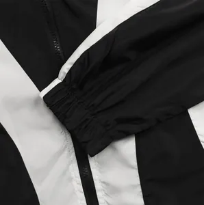 Detailansicht der schwarz-weißen Trainingsjacke mit elastischem Bündchen und Reißverschluss
