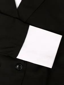 Close-up of black women's suit jacket featuring a contrast white cuff and classic button