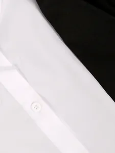 Close-up detail of white fabric with a white button and black contrast on a blazer.