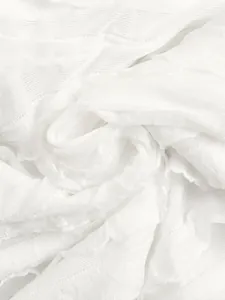 Dettaglio macro che mostra il tessuto pieghettato bianco di una leggera tuta estiva