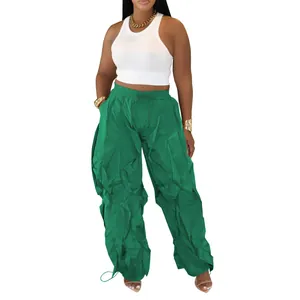 Detailed view of green pleated trousers with drawstring cuffs and wide-leg design