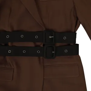 Detailed macro view of brown blazer featuring double black waist belts with buckles