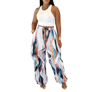Detail of woman's loose wide-leg pants with colorful abstract print and ruffle accents.