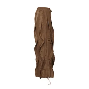 Detail view of brown pleated wide-leg trousers with unique ruffle design and drawstring hem.