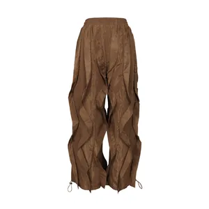 Close-up of brown pleated wide-leg trousers with vertical ruffle panels and drawstring hems