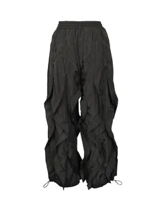 Detailed view of black ruffle pleated wide-leg trousers with adjustable drawstrings.