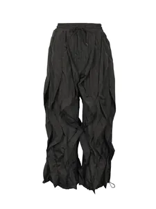 Detail view of black ruffled wide-leg trousers with multi-layered pleated design