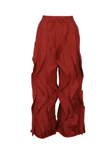 Front view detail of red wide-leg pleated trousers with layered ruffle design.