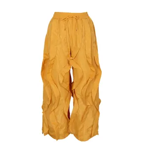 Close-up detail of yellow ruffled wide-leg pants with an elastic drawstring waist.