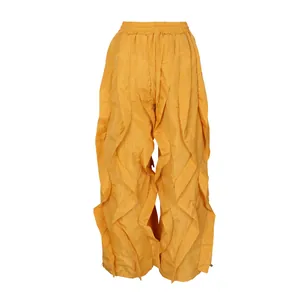 Detailed view of mustard yellow wide-leg trousers with tiered ruffles and pleated design.