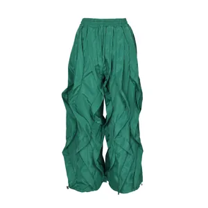 Detailed view of green ruffled wide-leg trousers with elastic waist and toggle hems.