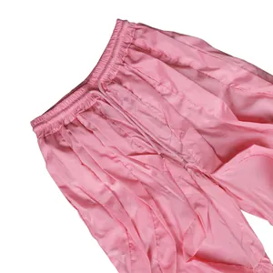 Close-up of pink pleated wide-leg trousers with elastic waistband and drawstring detail