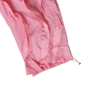 Detailed view of pink pleated wide-leg trousers with adjustable drawstring cuff