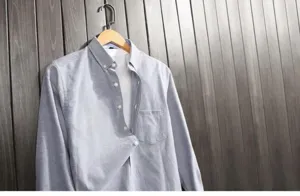 Close-up view of a grey long-sleeved Oxford shirt for men hanging on a wooden hanger