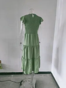 Detailed back view of a sage green flutter sleeve smocked tiered midi dress on mannequin