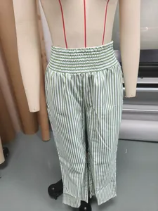 Detail view of green and white striped high waist trousers with smocked elastic waistband