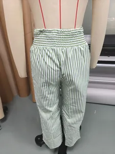 Detailed view of green and white vertical striped high-waisted trousers on a mannequin