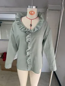 Detail of sage green cotton linen blouse featuring elegant ruffle trim along the neckline