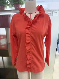 Detail of vibrant coral cotton linen top featuring elegant ruffle trim along the front placket.