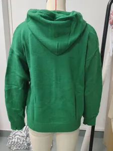 Detailed back view of a loose solid green knitted hooded pullover on a mannequin