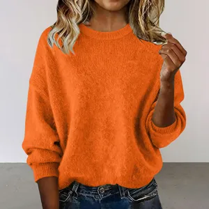 Detail view of a soft orange crewneck crop sweater with a loose and retro fit.