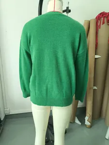 Back view of a loose green knit sweater showing soft texture and ribbed hem.