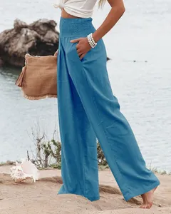 Détail d'un pantalon large en coton et lin bleu avec taille haute élastique smockée.